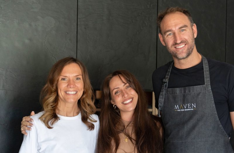 Rachel, homeowner, pictured alongside Ingrid, Senior Designer at Nolte Kitchens Henley-on-Thames, and Jack, Nolte neoChef, during the neoChef customer experience in Rachel's new dark kitchen, featuring textured neoSLATE stone veneer cabinetry.