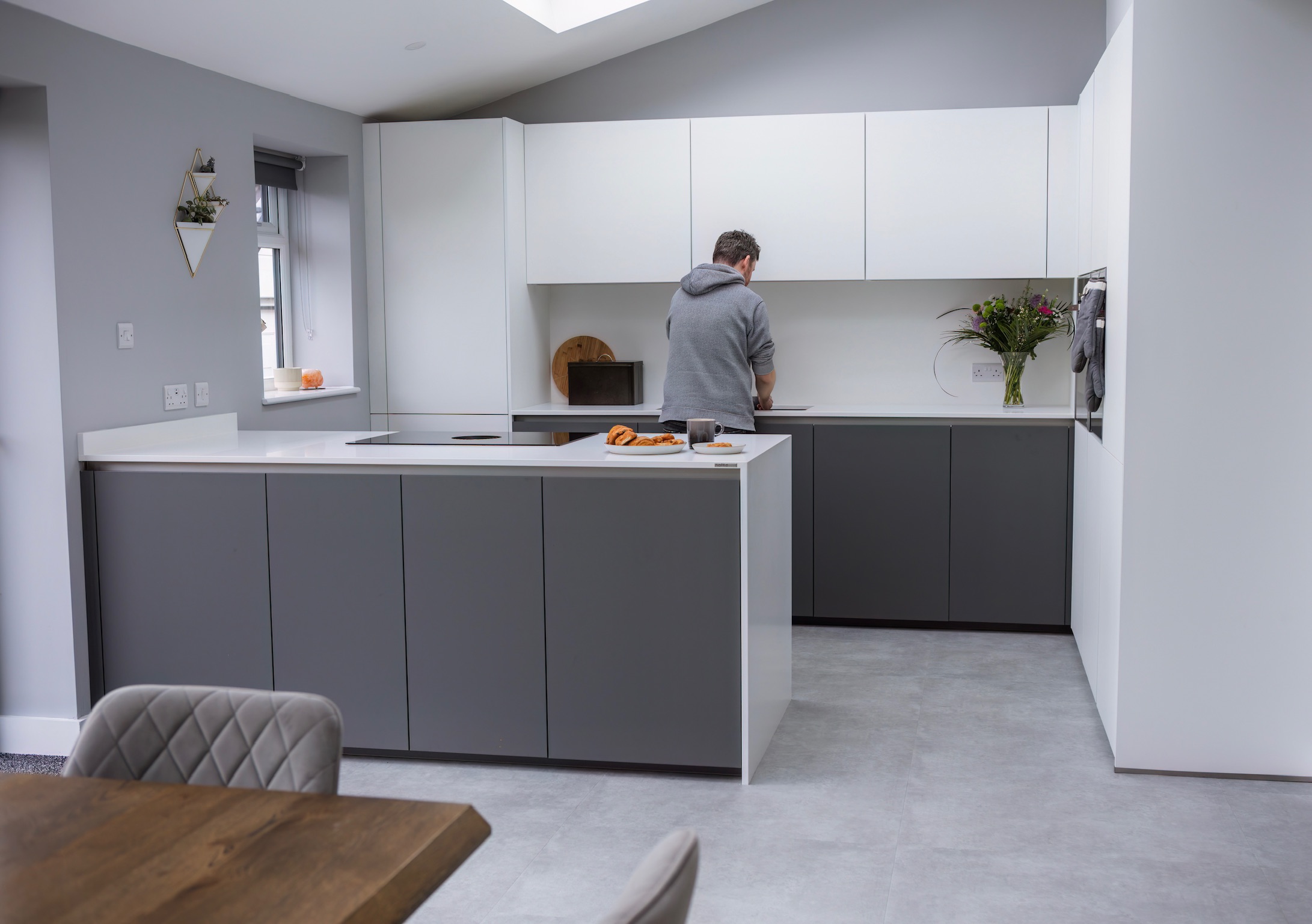 Modern handleless kitchen with dark grey and white cabinetry, shown in a real home setting