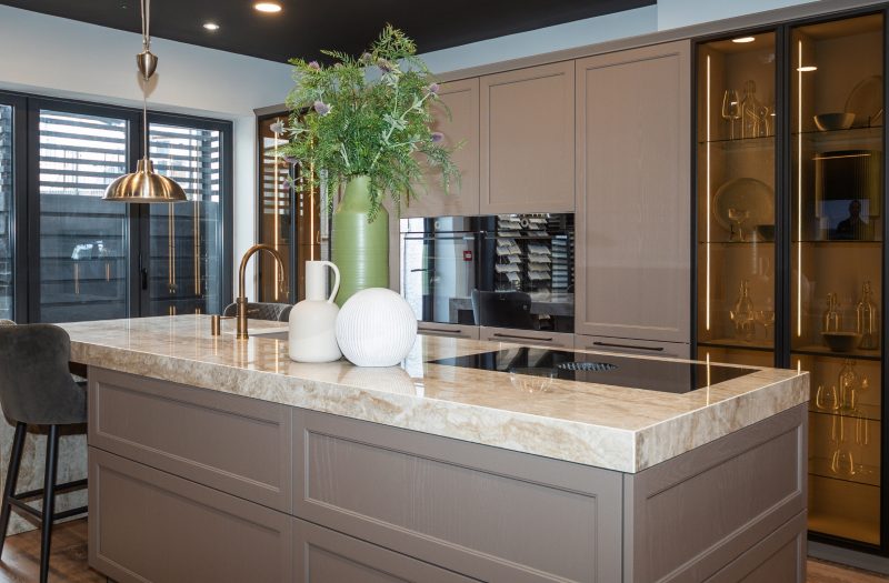Nolte Lugano Lack kitchen display at the Amersham showroom featuring a large stone island, integrated appliances and illuminated glass cabinetry.