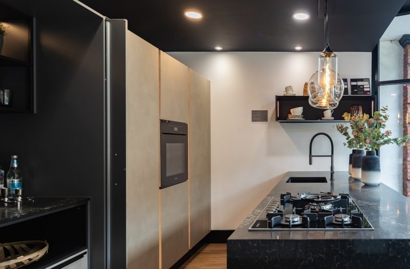 Nolte Portland kitchen display at the Amersham showroom with contemporary cabinetry, dark worktops, integrated oven, gas hob and open shelving.