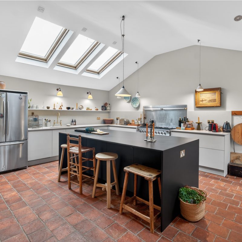 Plus Black island with Dekton waterfall worktop in a two-tone handleless kitchen with skylights, Wendover Buckinghamshire