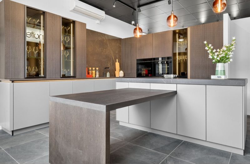 Nolte Kitchens Bath Showroom Full neoLodge kitchen display at Nolte Kitchens Bath with textured cabinetry, illuminated glass cabinets, handleless units and integrated appliances.