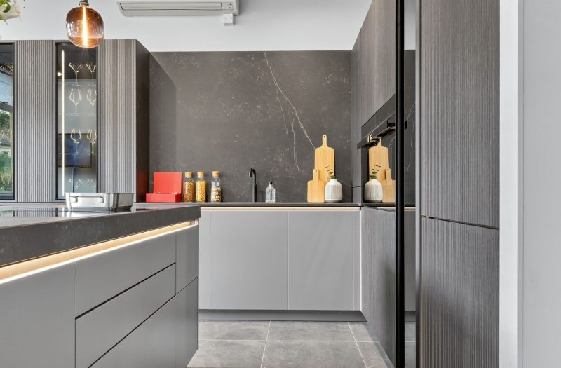 Detail of the neoLodge kitchen display at Nolte Kitchens Bath featuring handleless cabinetry, textured tall units, integrated appliances and illuminated grip rails.