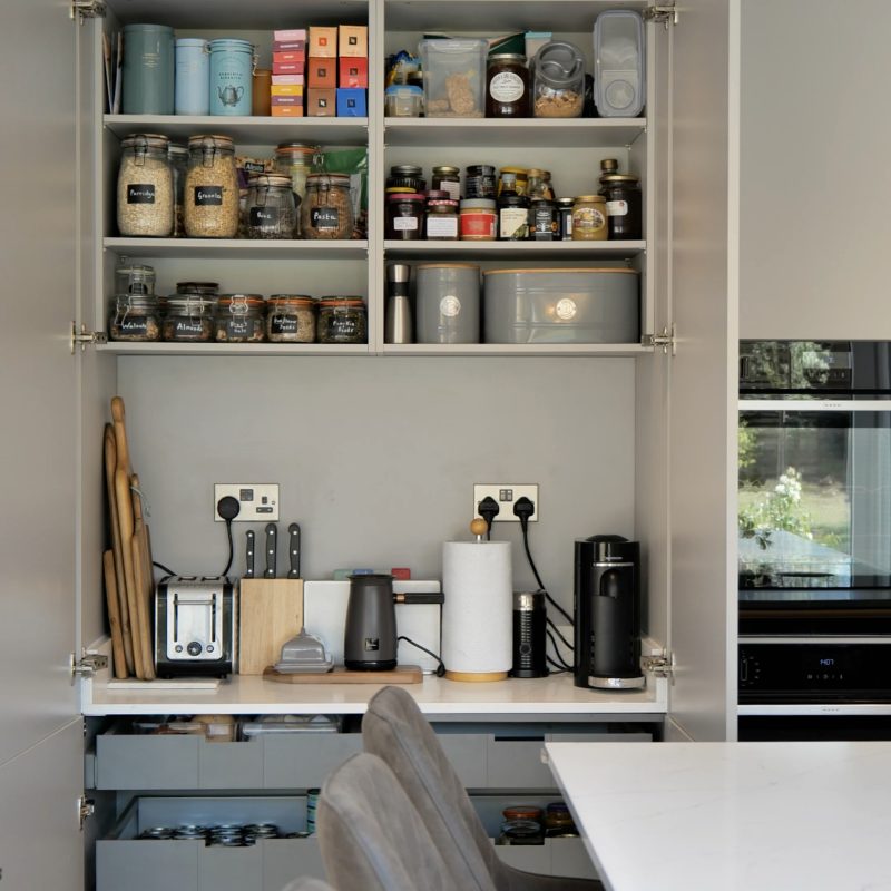 Hidden pantry with labelled jars and coffee machine in a Perfect Plus kitchen, Wilmslow