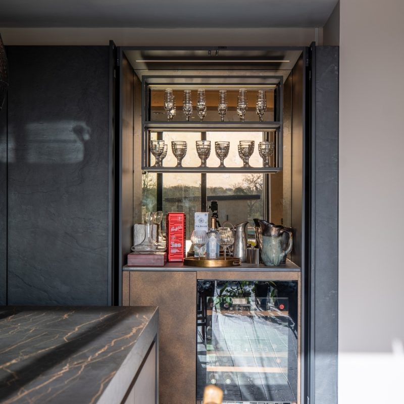 Home bar bantry with integrated wine cooler, glass display shelving and slide-away double doors