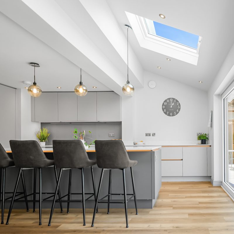 Contemporary hosting kitchen in Wilmslow with vaulted ceiling, skylight and island seating