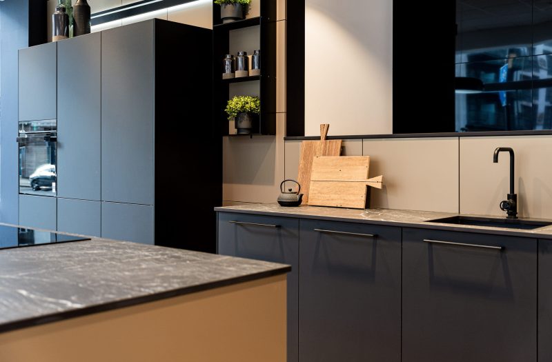 Contemporary Nolte kitchen at the Westminster showroom with dark black cabinetry, marble-effect worktops, integrated appliances and open shelving.