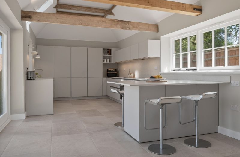 Bright contemporary Nolte Velluto Anti-Fingerprint kitchen in a Kent home, featuring soft neutral cabinetry, a breakfast bar and exposed timber beams.