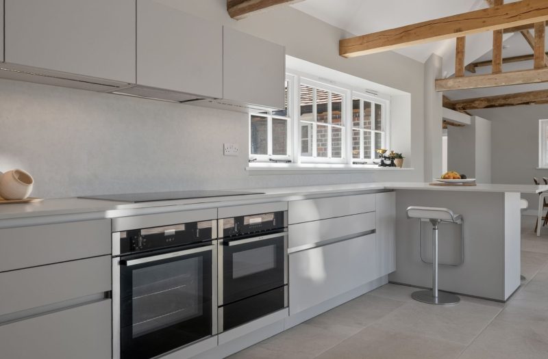 Bright contemporary Nolte Velluto Anti-Fingerprint kitchen in a Kent home, featuring soft neutral cabinetry, a breakfast bar and exposed timber beams.