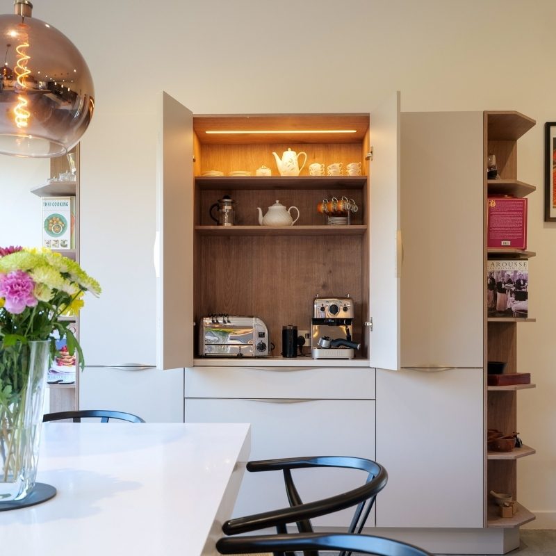 Bantry-style Nolte cabinetry opened to reveal a hidden coffee and breakfast station with integrated shelf lighting