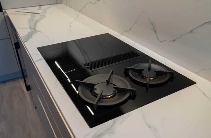 Black BORA hob with two burners and a built-in downdraft extractor, set into a white marble-effect Laminam worktop