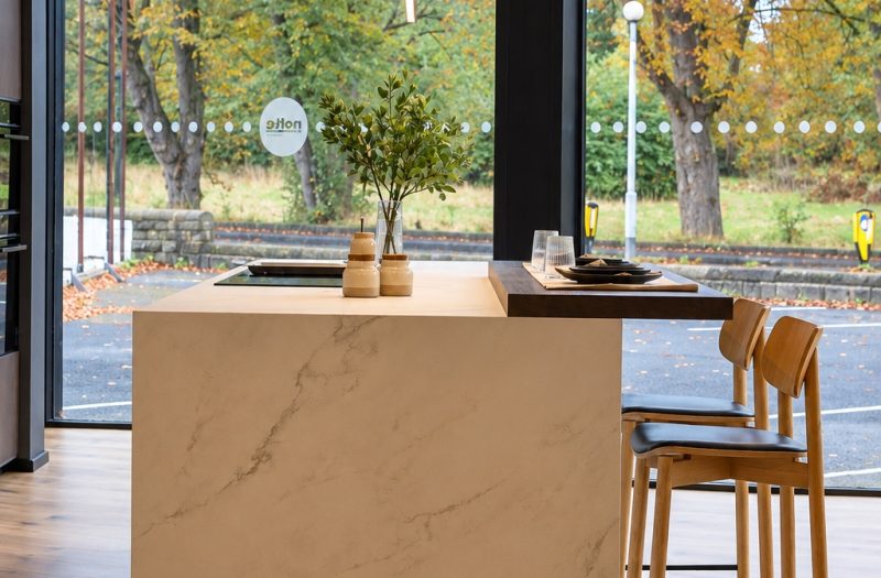 Marble-effect kitchen island with a dark wood breakfast bar and oak bar stools at the Nolte Wakefield showroom